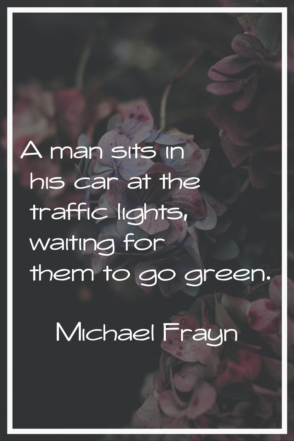 A man sits in his car at the traffic lights, waiting for them to go green.